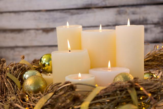 Candles and bauble ball in nest basket on wooden plank during christmas time