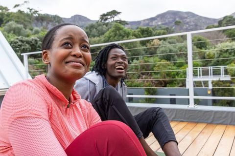 African american couple relaxing on rooftop deck in athletic wear smiling outdoor wellness