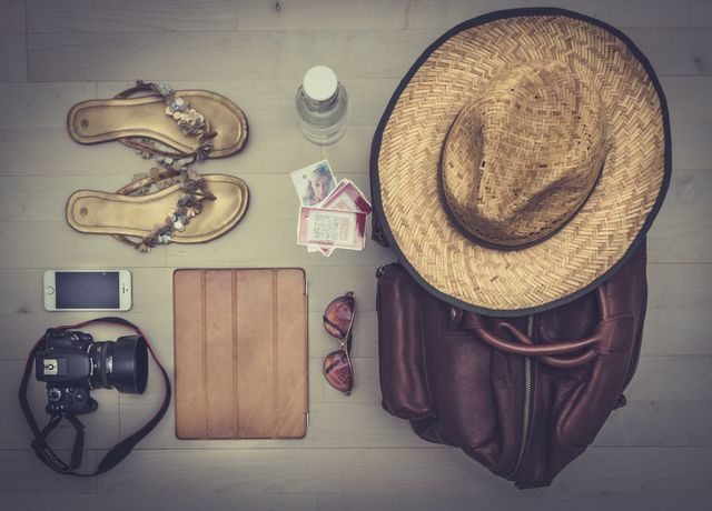 Showing various travel essentials neatly arranged on a wooden surface. Ideal for use in articles or posts about packing tips, travel preparation, or summer vacation ideas. Perfect for blogs, social media posts, or marketing materials catering to travelers and adventure enthusiasts.
