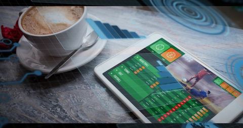 Tablet displaying sports analytics dashboard on cafe table with latte and hud overlays