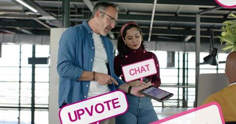 Professional pointing at tablet while collaborating with teammate in open-plan office