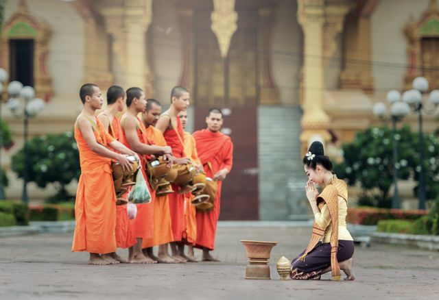 Thai woman making offerings to monks in traditional temple setting - Download Free Stock Photos Pikwizard.com