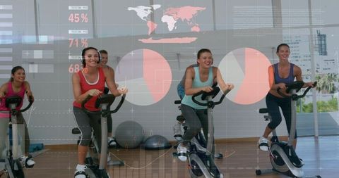 Energetic group spin class with women pedaling indoor bikes and data overlays