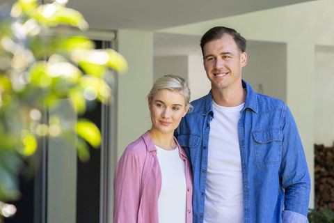 Young couple standing on modern covered porch smiling together during sunny afternoon