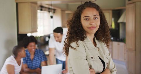 Confident Biracial Woman in Kitchen with Friends Using Technology
