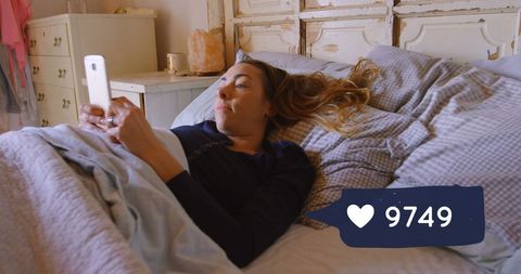 Woman in Bed Engaging with Social Media on Phone