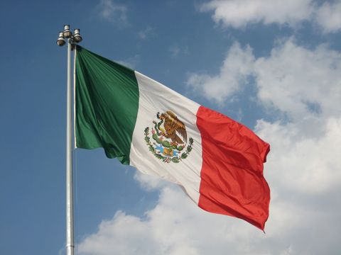 Mexican National Flag Waving Against Blue Sky
