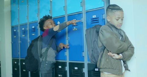 Children laughing and teasing in school hallway by lockers