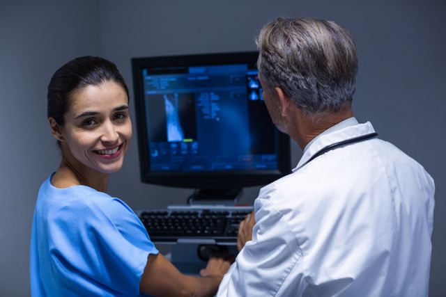 Doctor and nurse examining x-ray on computer in hospital. Ideal for use in healthcare, medical technology, and teamwork-related content. Perfect for illustrating medical examinations, patient care, and professional collaboration in a clinical setting.