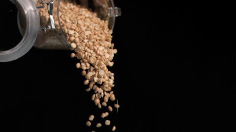 Peanuts Tumbling from Jar in Slow Motion on Black Background