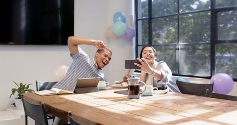 Colleagues celebrating office success with impromptu selfie at decorated workplace