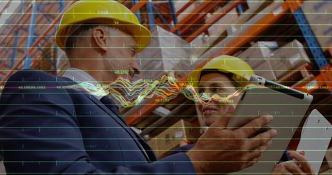 Warehouse supervisors reviewing tablet with digital data overlay in distribution center