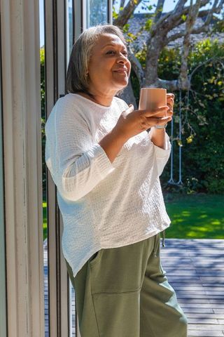 Senior Woman Enjoying Morning Coffee by Sliding Glass Door