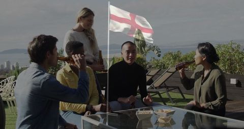 Friends enjoying drinks on rooftop terrace with engand flag in view