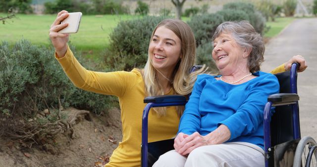 Smiling senior caucasian mother in wheelchair and adult daughter taking selfie together outdoors - Download Free Stock Photos Pikwizard.com