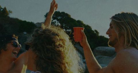 Friends Celebrating with Red Cups on Rocky Beach Cove