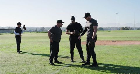 Baseball Teammates Discussing Glove and Ball During Sunny Practice on Grass Field
