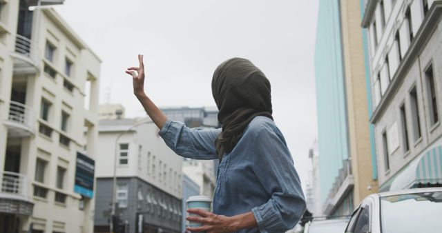 Woman Hailing Taxi on Urban Street while Holding Coffee Cup - Download Free Stock Images Pikwizard.com