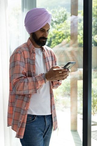 Middle-aged man checking smartphone indoors by glass door
