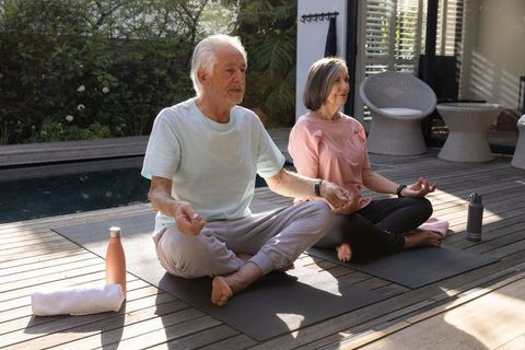 Senior Couple Practicing Meditation Outdoors on Deck