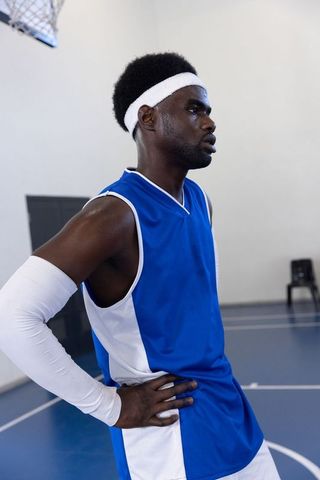 Basketball player pausing in gym wearing blue and white jersey