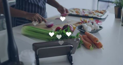 Home cook chopping fresh vegetables while following tablet recipe for healthy dinner