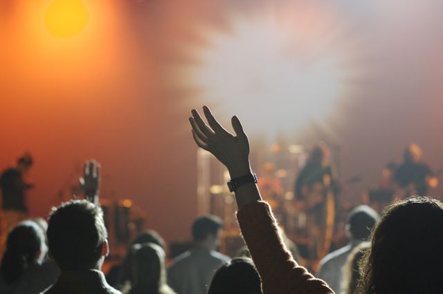 Diverse crowd of people with hands raised, enjoying a live music concert. Perfect for advertisements related to events, music festivals, nightlife activities, party promotions, and cultural gatherings.