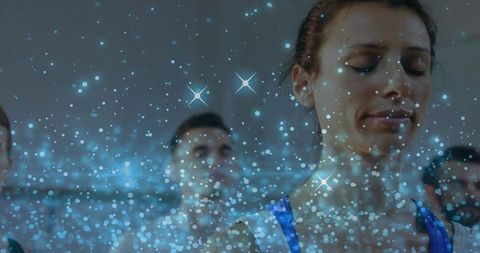 Meditating group practicing mindfulness in wellness studio with dreamy blue bokeh