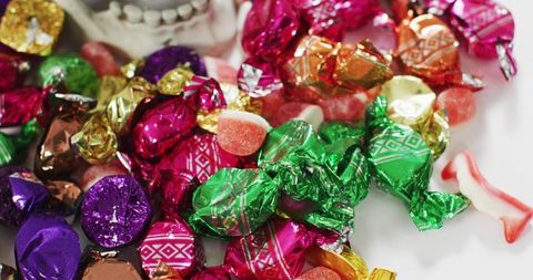 Colorful foil-wrapped candy assortment scattering across white plate closeup