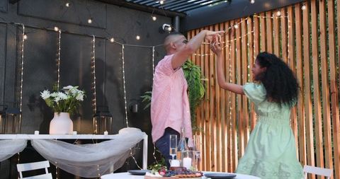 Couple dancing at romantic evening garden dinner with string lights