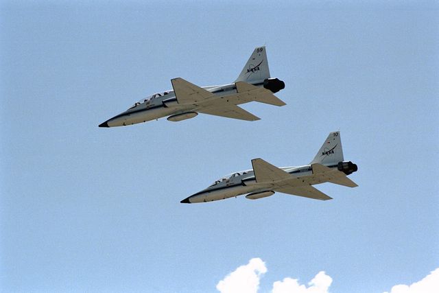 Two T-38 jets with STS-86 crew members fly over the space center during a training drill. This image captures the aircraft in perfect formation during the dress rehearsal for the Terminal Countdown Demonstration Test. This picture can be used in articles, educational materials, and presentations about NASA, aerospace training, and space exploration history.