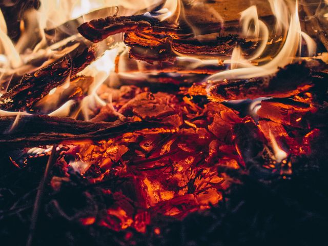 Close-up of glowing embers and flames, showcasing intense heat and burning wood. Ideal for use in articles about outdoor activities, camping, fire safety, survival skills, or as visual content for creating ambiance in marketing material.