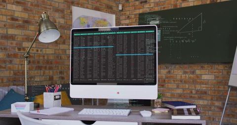 All-in-one computer displaying terminal windows on rustic desk with industrial chalkboard