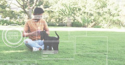 Asian man playing with black puppy on lawn holding purple ball casual outdoor leisure