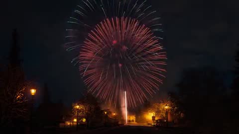 Vibrant Firework Display Over Snow-Covered Village Road at Night