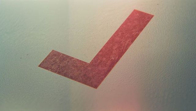 Red Check Mark on Pale Textured Wall