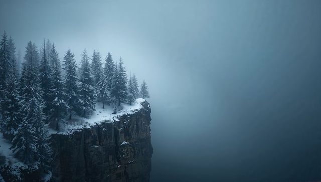 Snow-covered cliff-top spruce forest standing above misty alpine abyss with copy space