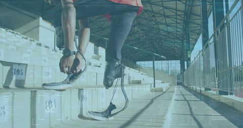 Athlete with prosthetic leg tying shoe on stadium stairs