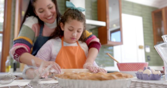 Mother and daughter enjoying a baking activity at home, creating a bond through cooking. Suitable for family-oriented content, parenting blogs, home cooking websites, and advertising campaigns focusing on family values and home life.