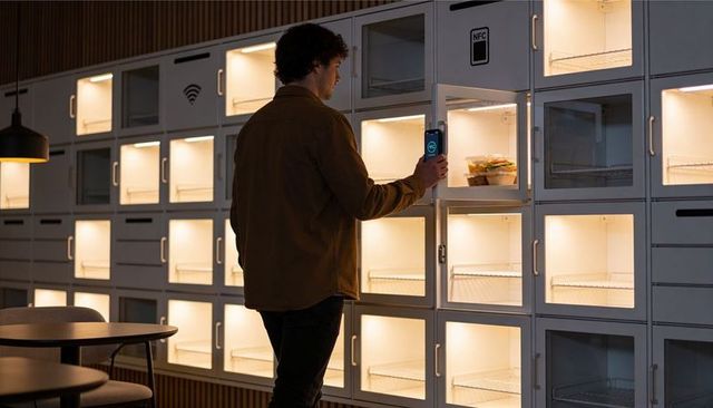 Scanning pickup with phone: man unlocking smart food locker wall to collect takeout order
