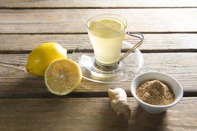 High angle view of tea cup with lemon and ginger on wooden table