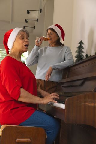 Senior Women in Santa Hats Singing at Piano in Festive Setting
