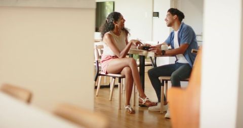 Young couple laughing and sharing moment at bright modern kitchen table, casual lifestyle
