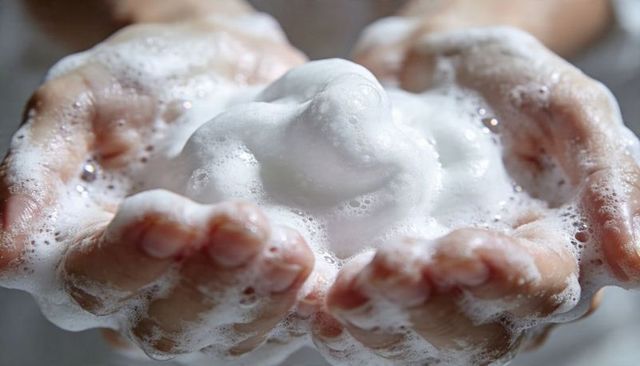 Cupping hands holding thick white soap foam closeup handwashing hygiene cleansing