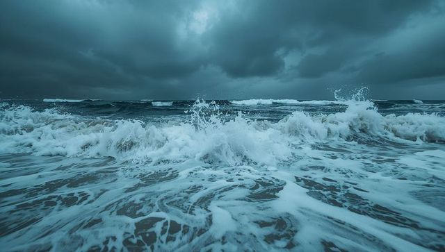 Moody ocean waves crashing into foamy surf under dramatic storm clouds