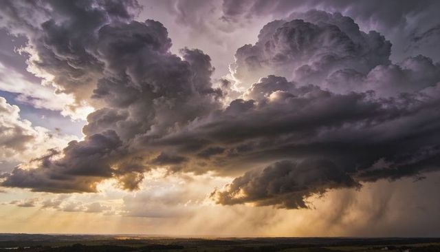 Towering Cumulonimbus Storm Cloud Over Farmland with Sunbeams and Rain Shafts, Golden-Hour Drama