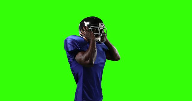 Male American football player wearing a blue uniform and helmet posing on a green screen backdrop. Suitable for image cutouts, sports stories, athlete promotions, and green screen keying in videos or graphic designs.
