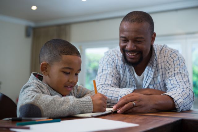 Father assisting his young son with homework in a cozy living room. Ideal for use in educational content, parenting blogs, family-oriented advertisements, and articles on home learning and parental support.