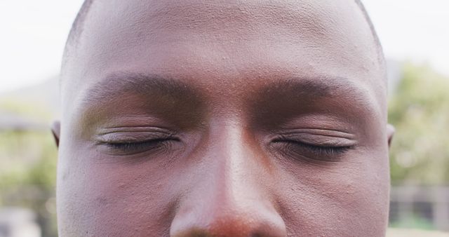 Close-up of a person's face with eyes closed in meditation outdoors. This image can be used in articles, blogs, and campaigns promoting mindfulness, relaxation, mental health, and outdoor activities.