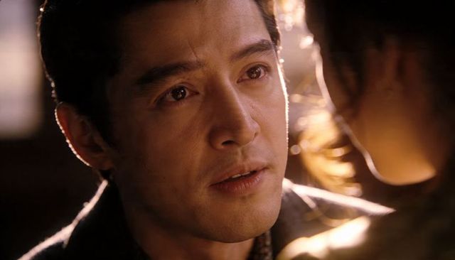 Moist-eyed asian man gazing in intimate backlit closeup, cinematic emotional portrait